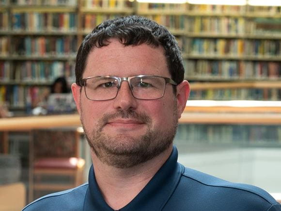 A man stands near the 2nd floor railing in the Hagerty Library