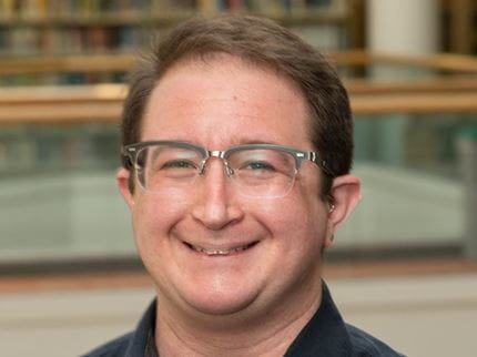 Man standing near library book shelves