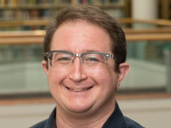 Man standing near library book shelves