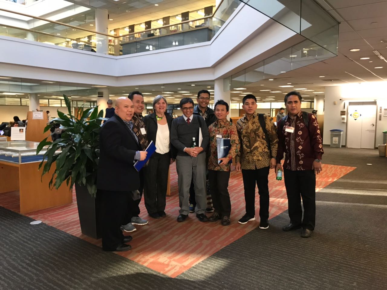 Seven men and one woman pose for a photo in the first floor of the W. W. Hagerty Library