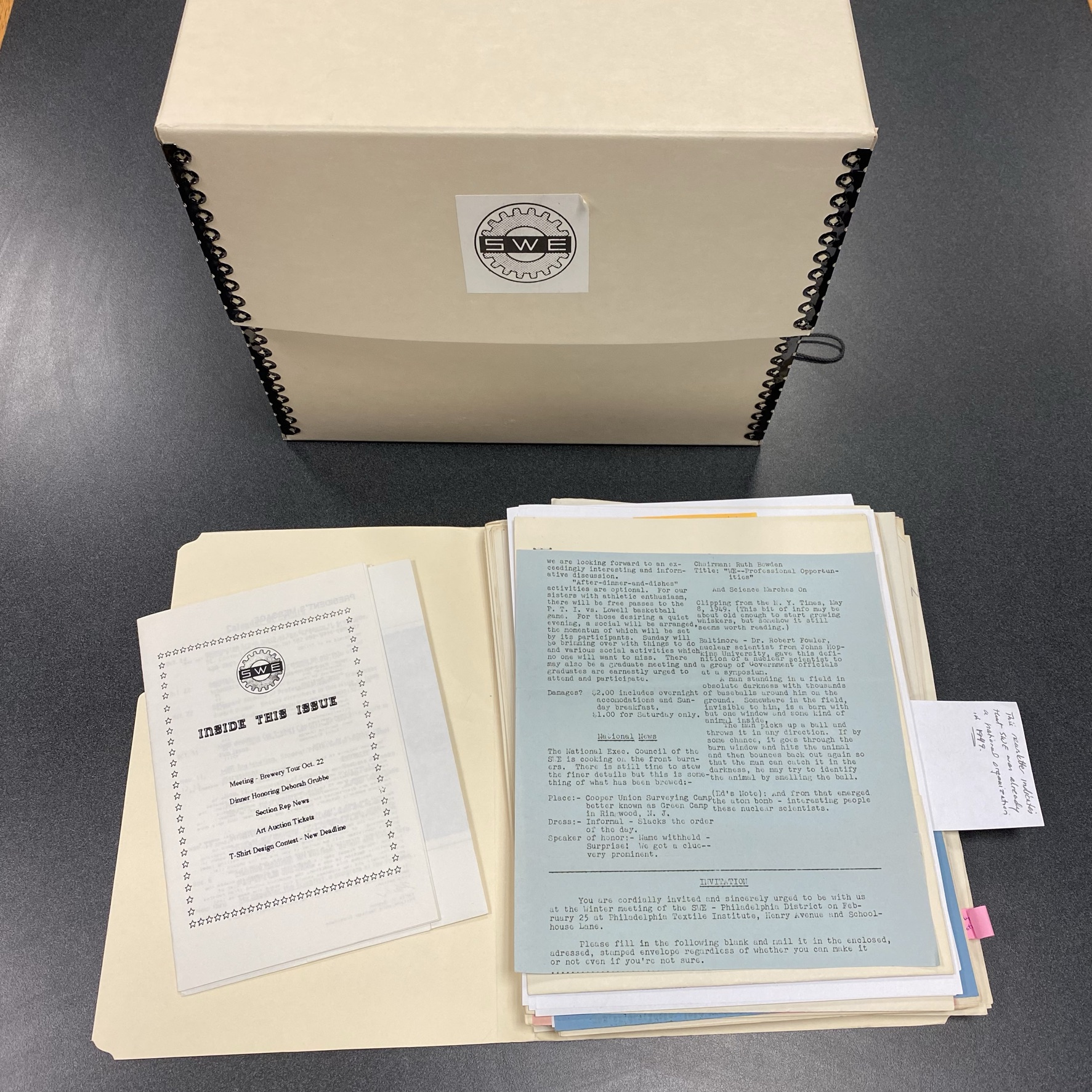 Archival file box with SWE logo with open file folder exposing type written documents from previous newsletters. 