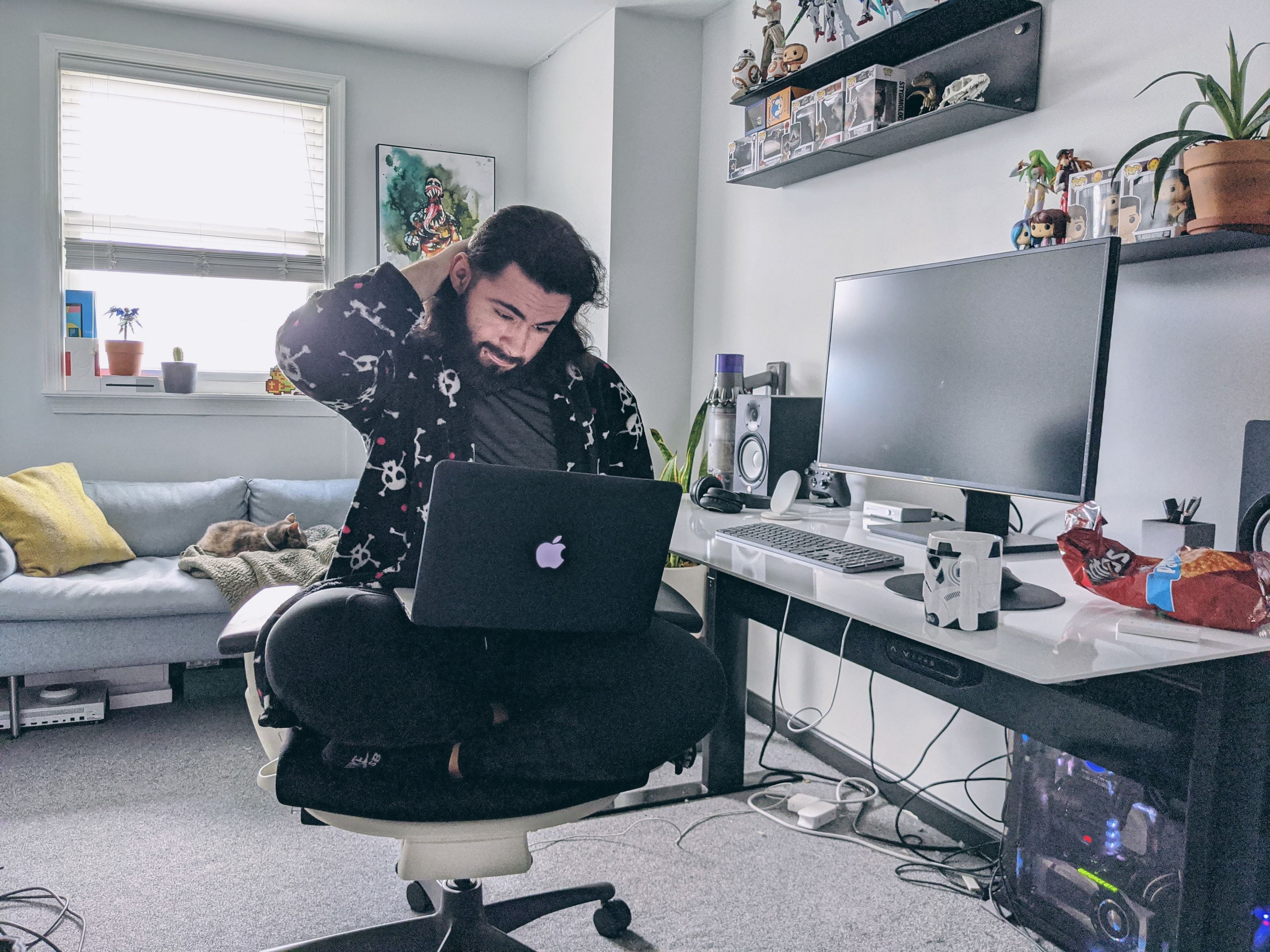 A man sits on a computer chair with a laptop 