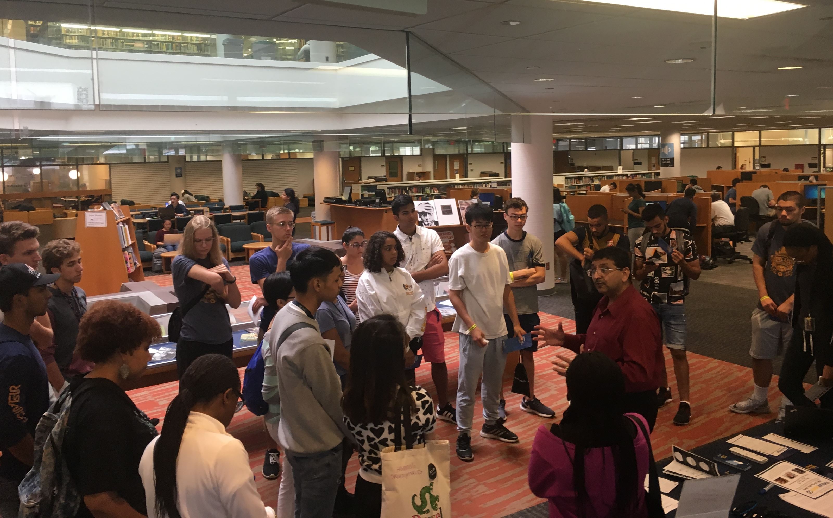 a group of young men and women stand in a circle around another man as he speaks to them